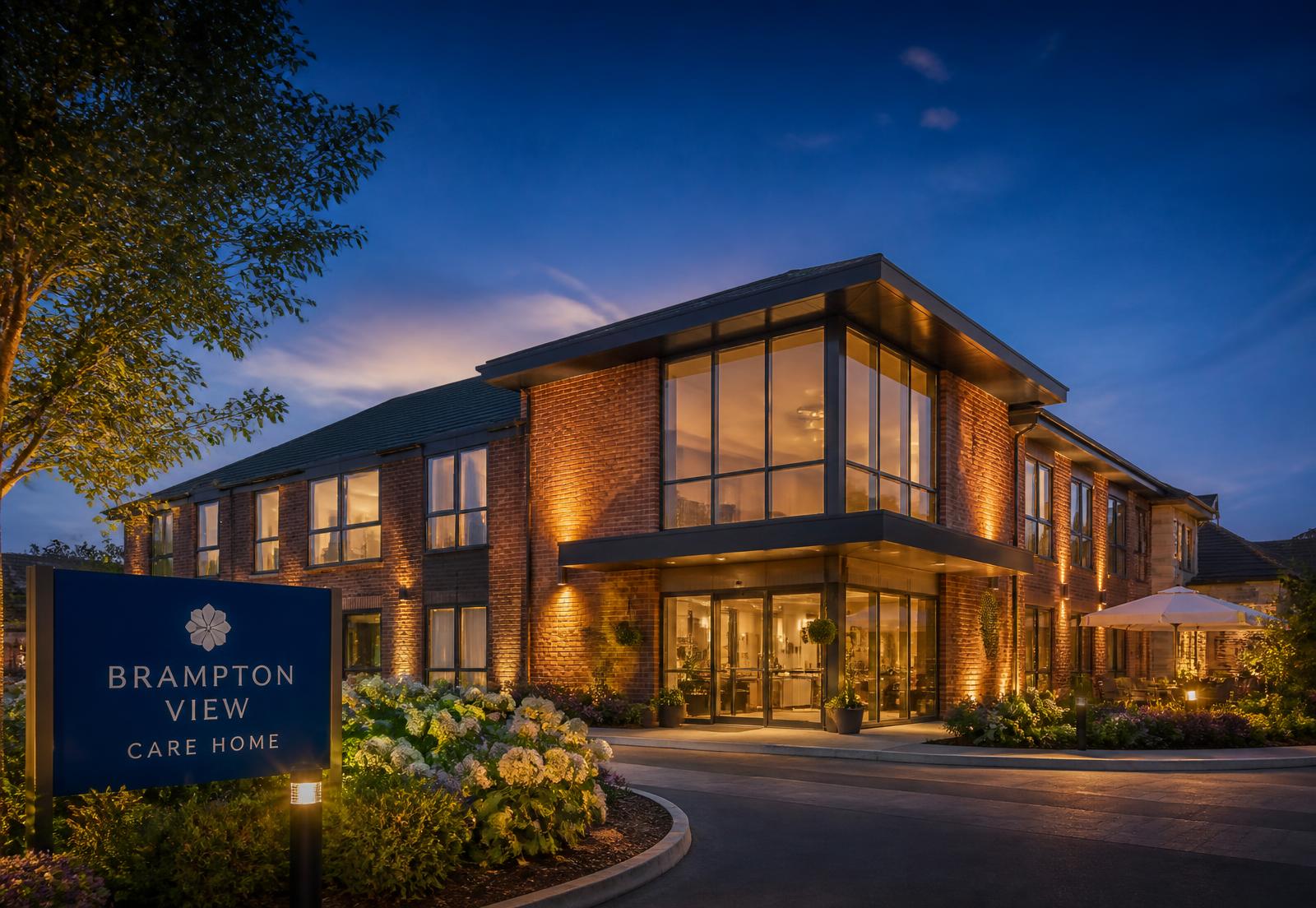A modern UK care home at dusk with lit windows and landscaped gardens